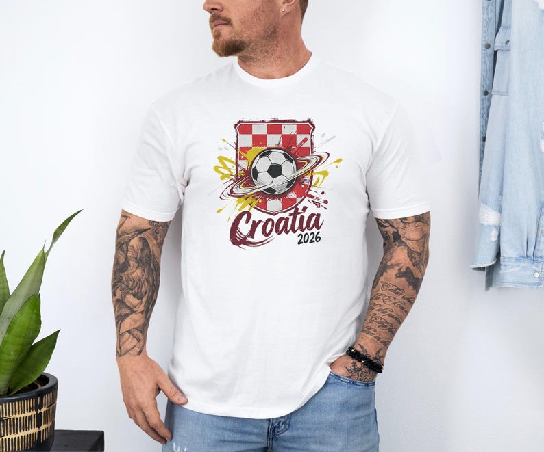 A man wearing a white t-shirt with a graphic of a soccer ball and a red and white checkered flag, along with the text "Croatia 2026".