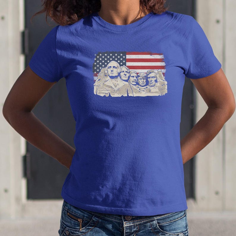A woman wearing a blue t-shirt with an American flag design featuring the faces of four prominent historical figures.