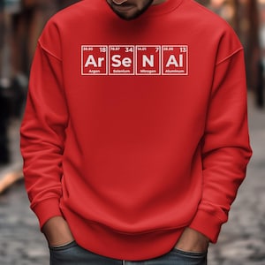 May include: A red sweatshirt with the word "Arsenal" spelled out using the periodic table elements Argon, Selenium, Nitrogen, and Aluminum. The sweatshirt is a solid red color.