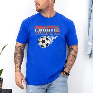 A man wearing a blue t-shirt with the word "Croatia" printed on it, standing against a white wall.
