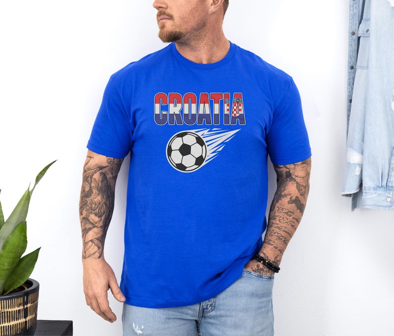 A man wearing a blue t-shirt with the word "Croatia" printed on it, standing against a white wall.