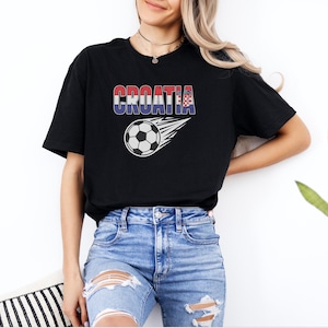 A woman wearing a black t-shirt with the word "Croatia" printed on it, standing against a white wall.