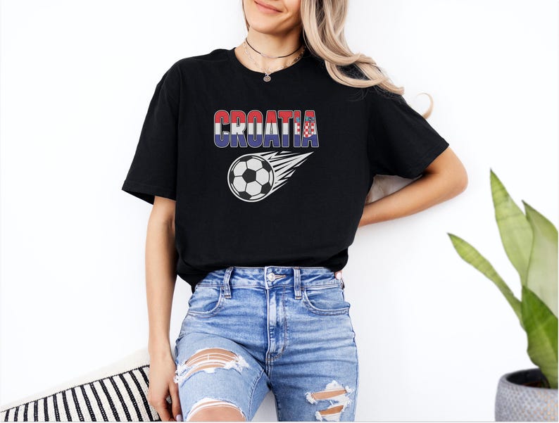 A woman wearing a black t-shirt with the word "Croatia" printed on it, standing against a white wall.