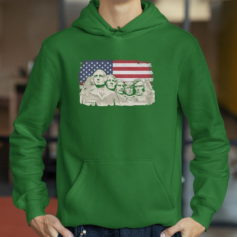 A person wearing a green hoodie with an American flag design featuring the Statue of Liberty.