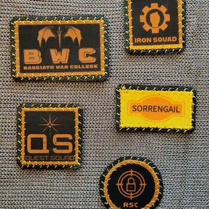 May include: Five embroidered patches with black and gold designs. The patches feature text such as "BWC Basciath War College", "Iron Squad", "Sorrengail", "Quest Squad", and "RSC". Each patch has a black border with yellow stitching.