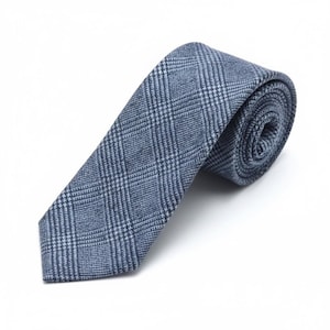 Puede incluir: Una corbata azul y blanca con un patr&oacute;n cl&aacute;sico de cuadros pr&iacute;ncipe de gales. La tela tiene una apariencia texturizada con un acabado tejido. La corbata est&aacute; enrollada en la parte superior y se estrecha hacia una punta, mostrando un dise&ntilde;o de cuadr&iacute;cula.