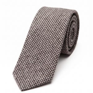 Puede incluir: Una corbata con un patr&oacute;n de pata de gallo en marr&oacute;n y blanco. La tela tiene una apariencia tejida y texturizada. La corbata est&aacute; enrollada en forma circular, mostrando claramente el extremo puntiagudo y la estructura del material enrollado.