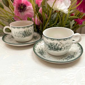 El precio incluye 1 taza y 1 platillo. Juego de taza y platillo decorativo. Rörstrand Suecia Grön Anna. Estampado floral verde oscuro. Presenta defectos, ver fotos.