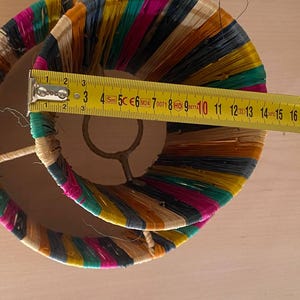 May include: A double-layered lampshade made of woven colorful strips of fabric. The lampshade is approximately 10 inches in diameter.