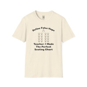 Puede incluir: Camiseta color crema con el texto "Define False Hope" sobre un gráfico de plano de asientos. Debajo del gráfico, la camiseta dice "Teacher: I Made The Perfect Seating Chart". La camiseta está hecha de un material suave y texturizado.