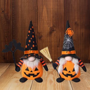 Könnte beinhalten: Zwei Halloween-Zwerg-Dekorationen. Jeder Zwerg hat einen orangefarbenen Kürbiskörper mit einem geschnitzten Kürbisgesicht. Einer trägt einen schwarzen Hut mit orangefarbenen Punkten, der andere einen Spinnennetz-Hut. Beide haben weiße Bärte und schwarz-orange gestreifte Arme.