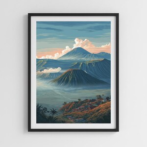 Op de afbeelding: Een ingelijste verticale kunstdruk met een vulkanisch landschap met een prominente kegelvormige berg in het midden, omringd door heuvels, mist en een klein dorp op de voorgrond onder een blauwe lucht met zachte roze en witte wolken.
