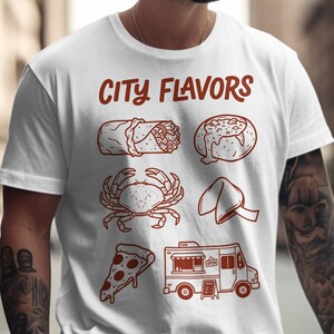 May include: White t-shirt with the text "CITY FLAVORS" in red. The shirt features illustrations of a burrito, crab, pizza slice, fortune cookie, and food truck. The design is in a simple, line-art style.