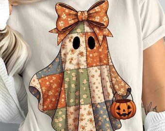 May include: A cream-colored t-shirt featuring a patchwork ghost design. The ghost has a large orange bow, black eyes, and a patchwork body with floral patterns in orange, green, and blue. It holds an orange jack-o'-lantern bucket, perfect for Halloween.