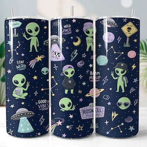Op de afbeelding: Een set van drie marineblauwe geïsoleerde bekers met een grillig alien-thema. Elke beker heeft groene aliens, UFO's, sterren en zinnen als "Stay Weird" en "Good Vibes". Het ontwerp bevat een Roswell, New Mexico-bord.
