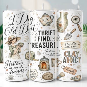 Può includere: Un bicchiere cilindrico bianco con illustrazioni di una persona con cappello, una teiera, una lente d'ingrandimento, una cazzuola, un forno e ceramiche. Il testo include I Dig Old Dirt, Thrift Find Treasure, Handle with care, Clay Addict e History in my hands.