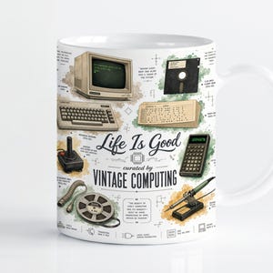 May include: A white ceramic mug featuring a vintage computing theme with illustrations of a retro computer, keyboard, floppy disk, joystick, calculator, and soldering iron. The text reads Life Is Good curated by VINTAGE COMPUTING.