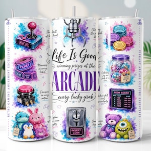 May include: Three white cylindrical tumblers with straws featuring colorful arcade-themed graphics. Designs include a joystick, tickets, a claw machine, plush toys, game tokens, a jar of prizes, and a high score board with the text Life Is Good winning prizes at the ARCADE.