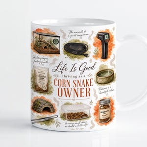 May include: A white ceramic mug featuring illustrations of corn snake care supplies, including a terrarium, heat mat, infrared thermometer, coconut husk substrate, water dish, hide, feeding tongs, and mealworms, with the text Life Is Good thriving as a CORN SNAKE OWNER.