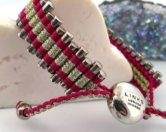 May include: A woven bracelet featuring alternating rows of magenta and metallic gold cord, accented with small silver-toned cylindrical beads. A round silver-toned toggle bead is engraved with the text LINKS LONDON and includes hallmark symbols.