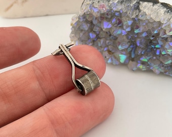 May include: A silver charm in the shape of a miniature roller, a common symbol of construction and building.
