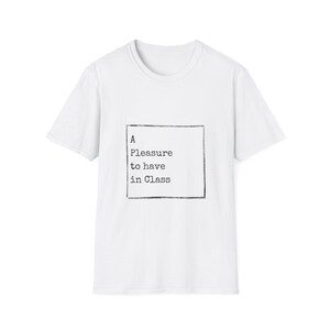 Op de afbeelding: Wit T-shirt met de tekst "A Pleasure to have in Class" in een zwart vierkant. Het shirt heeft een ronde hals en korte mouwen. De tekst is in een typemachine-lettertype.