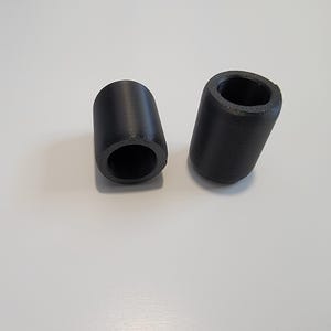 Puede incluir: Dos tapones de patas de muebles de goma negra. Los tapones son de forma cilíndrica con un centro hueco.