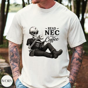 Peut inclure: Un t-shirt ivoire avec un motif noir représentant un squelette portant un casque de chantier et des lunettes de soleil, tenant une tasse de café et lisant un livre intitulé NEC National Electrical Code, avec le texte READ NEC AND Coffee.