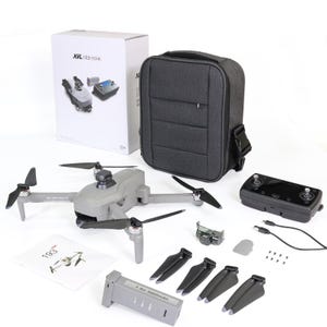 May include: A gray drone with four propellers, a remote control, a battery, a carrying case, and other accessories. The drone has a camera on the front and the text "XIL 193" on the side. The carrying case is gray and has a shoulder strap. The battery is gray and has the text "7.6V 3000mAh" on it.