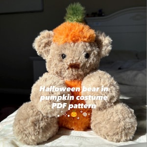 May include: A plush teddy bear in a pumpkin costume. The bear is light brown with an orange pumpkin body and a green stem on its head. The text "Halloween bear in pumpkin costume PDF pattern" is visible.