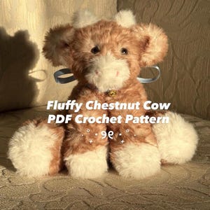 Puede incluir: Una vaca de peluche suave y esponjosa, en tonos marrón castaño y blanco. El peluche tiene una pequeña campana dorada y una cinta azul. El texto en la imagen dice "Fluffy Chestnut Cow PDF Crochet Pattern".