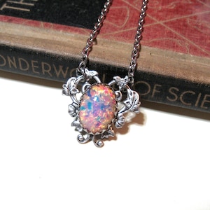 Könnte beinhalten: Eine silberne Halskette mit einem rosafarbenen Opal-Edelstein, der in einem floralen Design gefasst ist.
