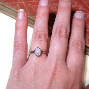 May include: A silver ring with a white opal gemstone set in a delicate, ornate setting.