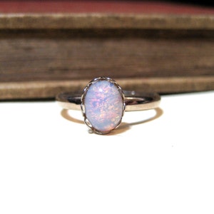 May include: A silver ring with a white opal gemstone set in a delicate, ornate silver setting.