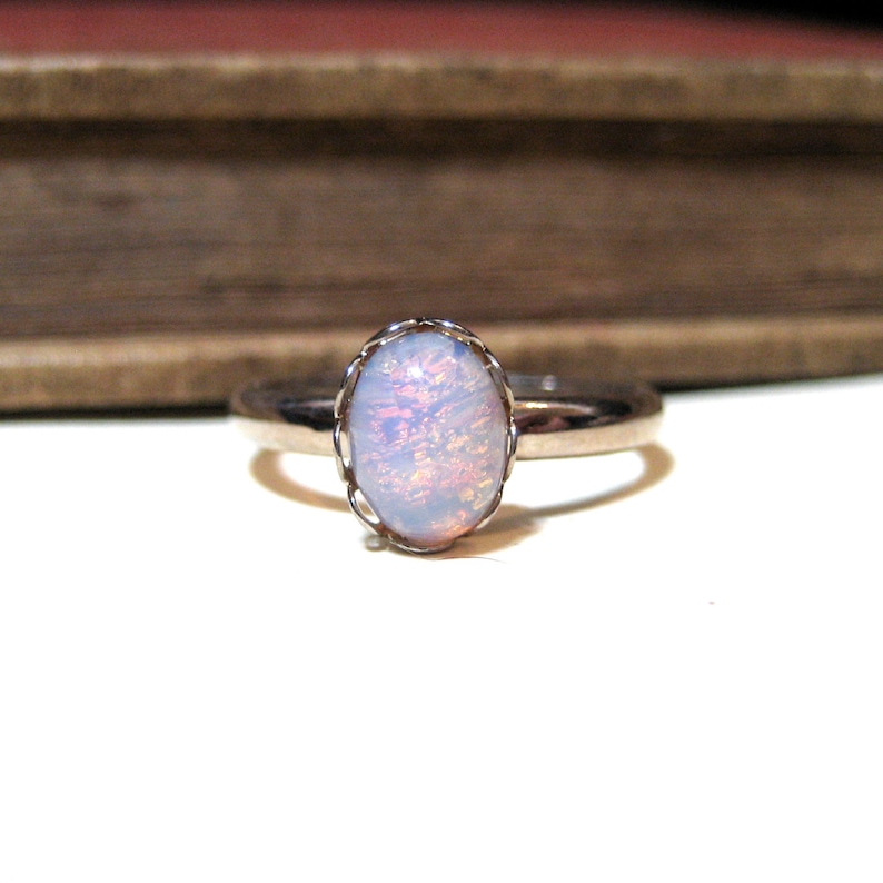 May include: A silver ring with a white opal gemstone set in a delicate, ornate silver setting.