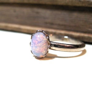 May include: A silver ring with a white opal gemstone set in a delicate floral design.