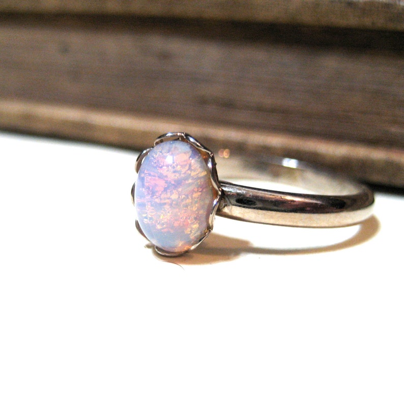 May include: A silver ring with a white opal gemstone set in a delicate floral design.