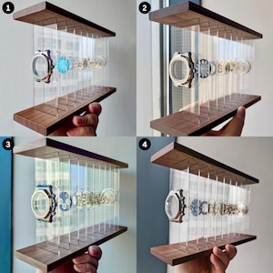 Könnte beinhalten: Ein Uhrenständer mit einem Sockel und einer Oberseite aus dunklem Holz, die durch mehrere vertikale, transparente Acrylplatten verbunden sind. Der Ständer hält ein zerlegtes Uhrwerk, dessen Komponenten in einer linearen Explosionsansicht angeordnet sind.