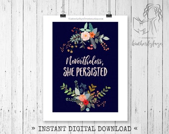 Puede incluir: Una impresión digital con fondo azul marino y las palabras "Nevertheless, She Persisted" en escritura blanca. Arreglos florales en rosa, naranja y verde rodean el texto. La impresión está sujeta por una pinza negra.