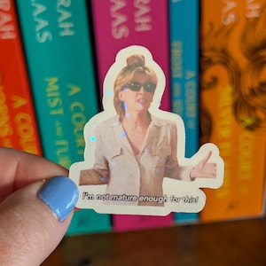 May include: A die-cut holographic sticker featuring a person with blonde hair wearing dark sunglasses and a light-colored button-down shirt. The person has their arms outstretched, and the text below reads, I'm not mature enough for this!