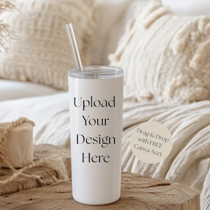 May include: A white tumbler with a clear straw and a silver lid. The text "Upload Your Design Here" is printed vertically on the tumbler. A small, round sticker with text is also visible.