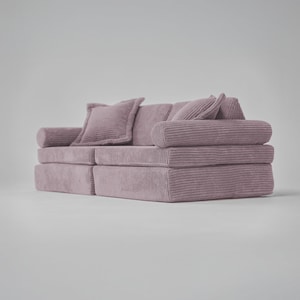 Op de afbeelding: Een roze corduroy bank met twee kussens. De bank bestaat uit twee aparte delen die aan elkaar kunnen worden bevestigd.
