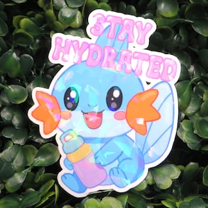 May include: A sticker featuring a blue cartoon creature holding a water bottle, with the text "STAY HYDRATED" in pink above it. The sticker has a holographic effect and is set against a background of green leaves.