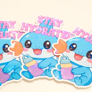 May include: Three stickers featuring a cartoon character with blue and light blue coloring, holding a water bottle. The stickers have the text "STAY HYDRATED" in pink, with a cute, friendly design.