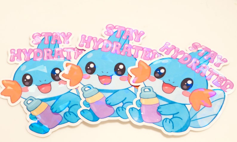 May include: Three stickers featuring a cartoon character with blue and light blue coloring, holding a water bottle. The stickers have the text "STAY HYDRATED" in pink, with a cute, friendly design.