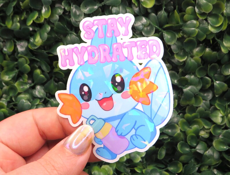 May include: A holographic sticker featuring a cartoon character with blue, orange, and pink accents, holding a water bottle. The sticker has the words "STAY HYDRATED" in pink bubble letters.