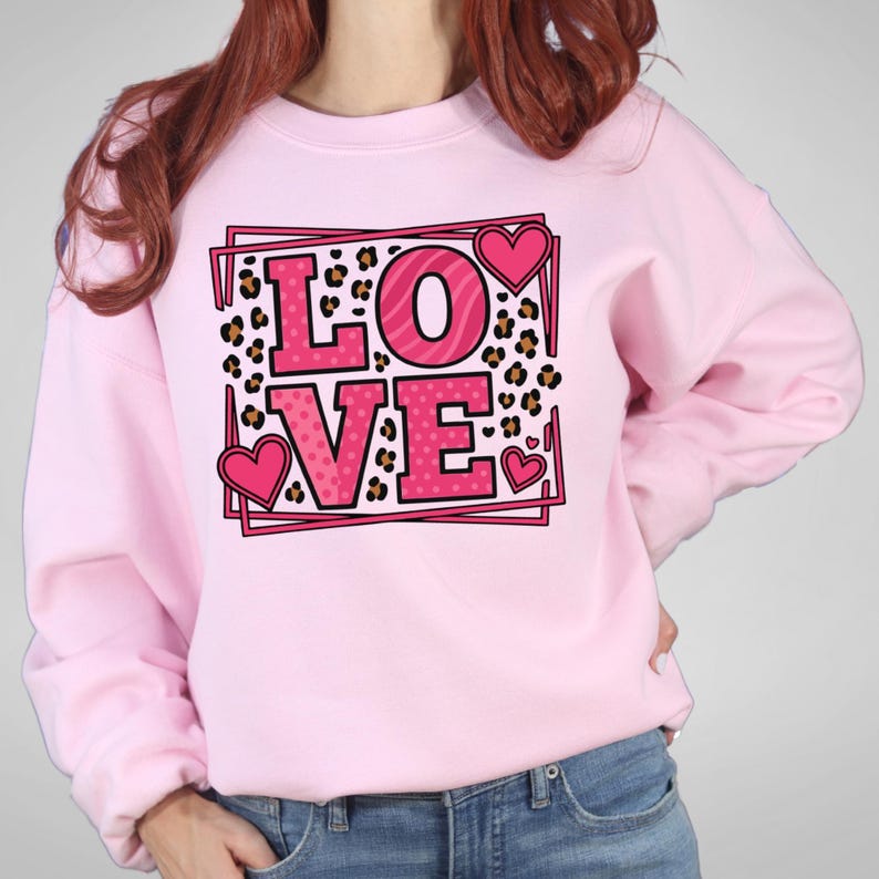 May include: A light pink sweatshirt with the word "LOVE" in a pink and leopard print design. The "L" and "E" are pink with polka dots, and the "O" and "V" have a zebra print. Pink hearts are on the design.
