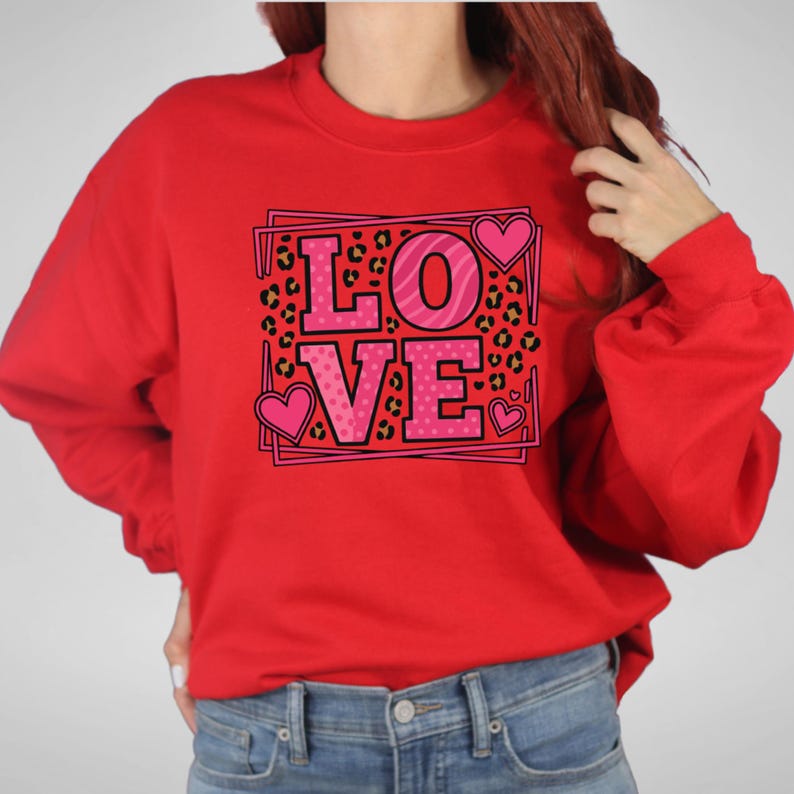 May include: Red sweatshirt with the word "LOVE" in pink letters. The letter "O" has a zebra stripe pattern, and the letters "L", "V", and "E" have a pink heart design. The background has a leopard print.