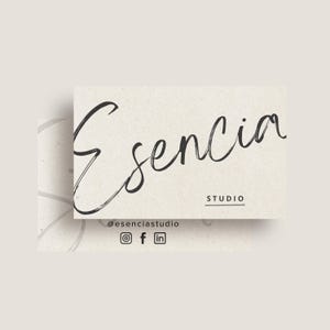Könnte beinhalten: Eine Visitenkarte mit dem Wort "Esencia" in einer stilisierten Schreibschrift. Das Wort "Studio" ist unter dem Wort "Esencia" gedruckt. Der Text "@esenciastudio" ist unter dem Wort "Studio" gedruckt. Social-Media-Symbole für Instagram, Facebook und LinkedIn sind unter dem Text "@esenciastudio" gedruckt.