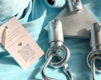 May include: A light blue aerial silk fabric roll paired with a silver-colored triangular metal rigging plate and two swivel carabiners. A small rectangular tag is attached, featuring a QR code and the text LI.CIRQUE.